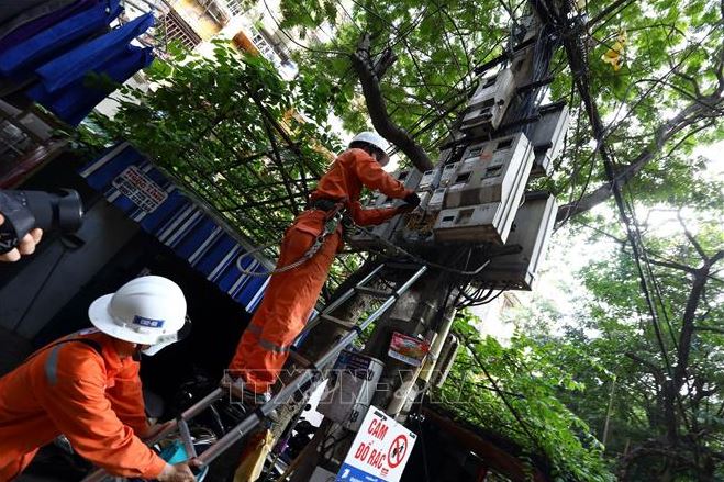 Công nhân Công ty Điện lực Hai Bà Trưng (Hà Nội) kiểm tra tiếp xúc tại hòm công tơ cấp điện cho hộ dân tại khu vực phường Quỳnh Lôi. Ảnh minh họa: Huy Hùng/TTXVN.