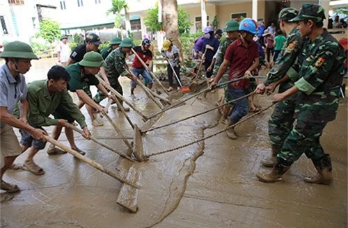 Phụ huynh, giáo viên cùng cùng lực lượng chức năng thu dọn bùn tại trường Tiểu học thị trấn Mường Xén (Kỳ Sơn) sáng 19/8. Ảnh: Nguyễn Hải.