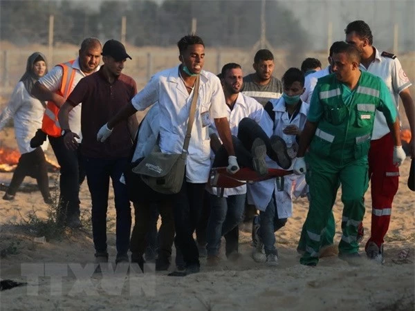 Chuyển người biểu tình Palestine bị thương tại khu vực biên giới Gaza- Israel ngày 3/8. (Ảnh: AFP/TTXVN)