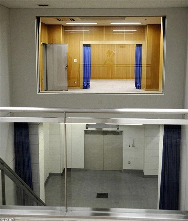 Phòng “treo”: Phòng ốp gỗ phía trên, rèm cửa màu xanh dương, là nơi tù nhân bị treo cổ.Một sợi dây thừng sẽ được quấn quanh cổ tù nhân và sau đó họ bị thả rơi xuống phòng lát gạch màu xám bên dưới. Ảnh: AP