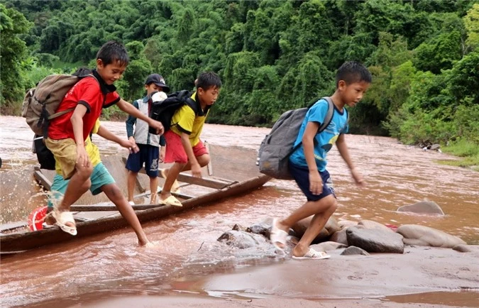 Học sinh phải đi thuyền vượt qua 2 con suối chảy xiết tới trường dự Lễ khai giảng năm học mới. (Ảnh: Việt Hoàng/TTXVN)