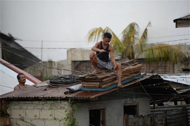 Ở khu vực phía bắc Philippines, người dân đã dùng các thanh gỗ để gia cố các cửa sổ bằng kính, đồng thời dùng dây thừng để cố định mái nhà, tránh trường hợp bị gió thổi bay. (Ảnh: AFP)