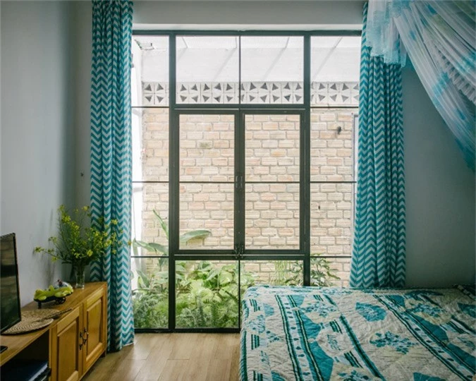 Phòng ngủ với những ô cửa kính hứng ánh sáng tự nhiên và nội thất màu dịu nhẹ.
