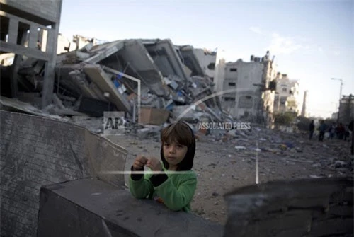 Cậu bé Palestine đứng bên cạnh đống đổ nát của tòa nhà Đài truyền hình Al-Aqsa của Hamas sau vụ không kích. Ảnh: AP