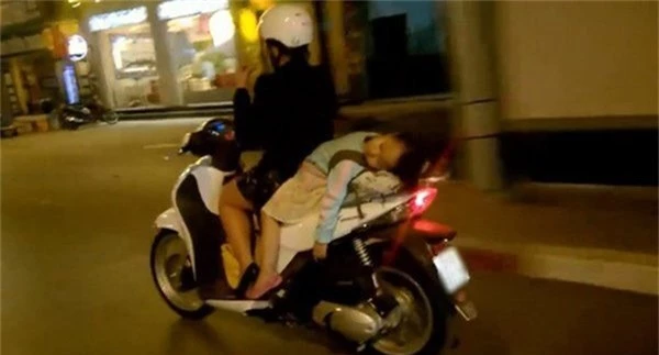 Bà mẹ 1 tay lái xe máy, 1 tay ôm con bú trên đường
