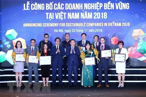 Phó Thủ tướng Chính phủ Vương Đình Huệ và Chủ tịch VCCI Vũ Tiến Lộc trao chứng nhận cho các doanh nghiệp 3 năm liền nằm trong top 10 doanh nghiệp bền vững. (Ảnh: Minh Quyết/TTXVN)
