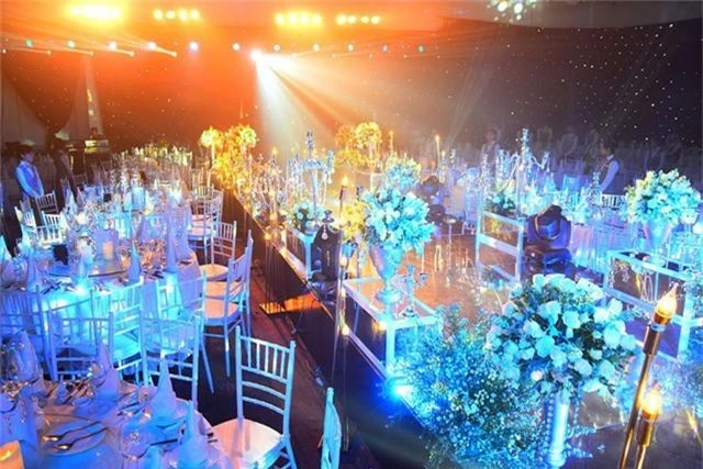 Không gian tiệc cưới được trang hoàng cầu kỳ và lộng lẫy bằng đèn chùm pha lê và hoa tươi với tông trắng chủ đạo và nổi bật.