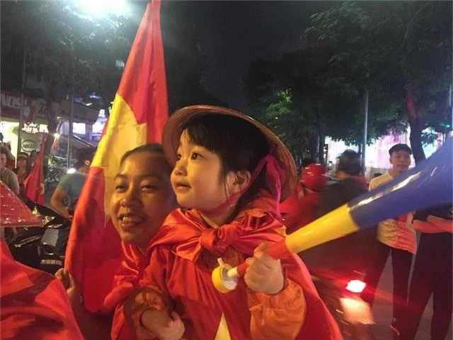 Trẻ nhỏ theo người lớn đi ăn mừng chiến thắng cho đội tuyển Việt Nam.