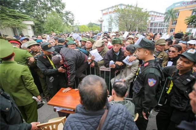 Một người trèo qua hàng rào chen lấn tới chỗ làm thủ tục đăng ký vé.