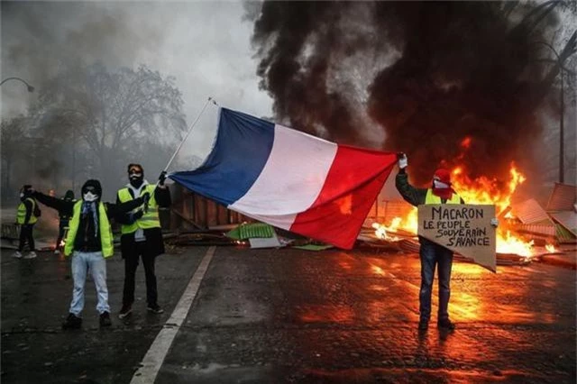  Người biểu tình Áo vàng cầm cờ Pháp phản đối chính quyền Macron tại Paris. (Ảnh: AFP) 