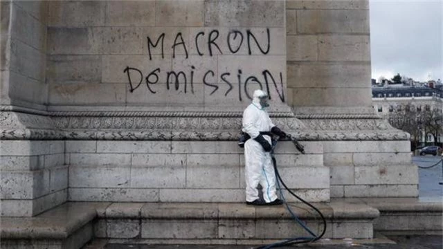  Một công nhân tìm cách xóa dòng chữ do người biểu tình viết đòi Tổng thống Macron từ chức tại Khải Hoàn Môn ở Paris. (Ảnh: AP) 