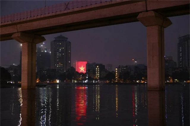 Một tòa nhà trang trí đèn hình lá cờ đỏ sao vàng khổng lồ nhìn từ hồ Hoàng Cầu.