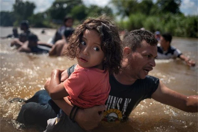  Angel Jesus, bé gái 5 tuổi từ Honduras, được bế qua sông Suchiate khi đoàn người di cư của các nước Trung Mỹ vượt qua Guatemala để vào lãnh thổ Mexico hôm 29/10. Đây là hành trình của đoàn di cư tiến tới biên giới Mỹ. 