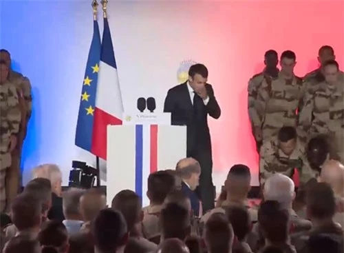 Tổng thống Macron bất ngờ khi một binh sĩ ngất xỉu bên cạnh. (Ảnh: RT)