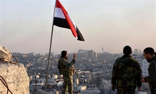 Quân đội Syria giương cờ tại một khu vực vừa được giải phóng. Ảnh Reuters