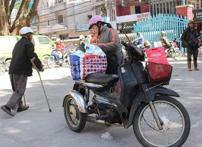 Một cô khuyết tật chăm chút buộc chặt phần quà tết để chở về (Ảnh: VH)