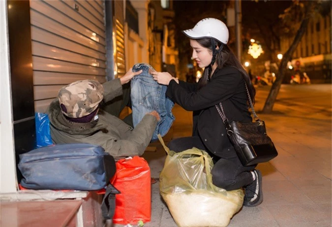 Á hậu được bạn chở bằng xe máy, rong ruổi qua từng con phố của thủ đô để tặng quà cho người vô gia cư. 
