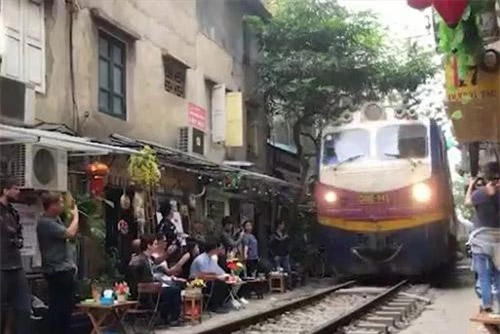 Du khách nước ngoài háo hức uống cà phê, đợi check-in khi tàu hỏa chạy sát qua. Du khách nước ngoài háo hức uống cà phê, đợi check-in khi tàu hỏa chạy sát qua.