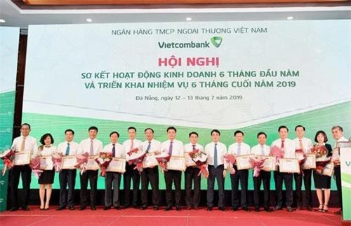 Chủ tịch HĐQT Vietcombank Nghiêm Xuân Thành (thứ 7 từ phải sang) và Tổng giám đốc Phạm Quang Dũng (thứ 6 từ trái sang) trao Giấy khen và tặng hoa cho 14 chi nhánh tiêu biểu trên một số mặt hoạt động 6 tháng đầu năm 2019