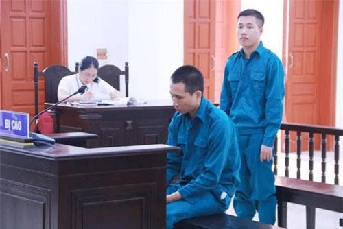 Hai đối tượng Phạm Văn Cửu (ngồi) và Nguyễn Công Hoan (đứng) tại phiên tòa.