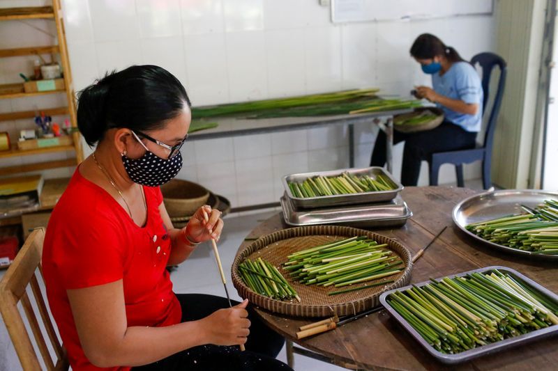 Nhân viên cửa hàng 3T làm ống hút từ cỏ bàng. (Ảnh: Reuters)