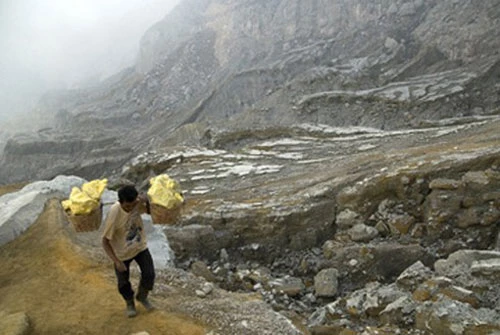 Một người thợ mỏ đang gánh những tảng lưu huỳnh nặng khoảng 70kg.