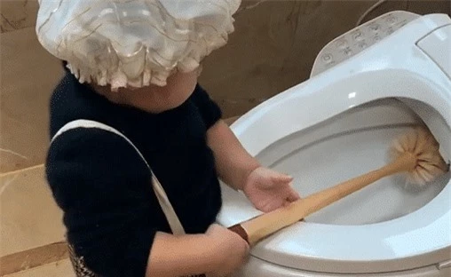 Cậu bé cầm chổi cọ toilet vô cùng tỉ mẩn.