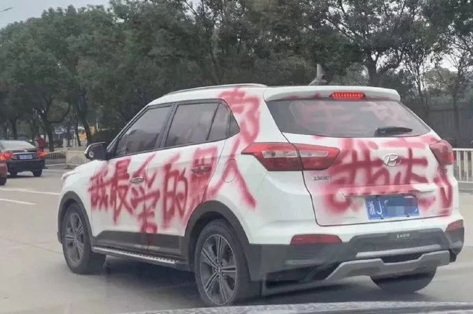 Chiếc xe ô tô bị phun sơn đỏ đang đỗ trên đường.