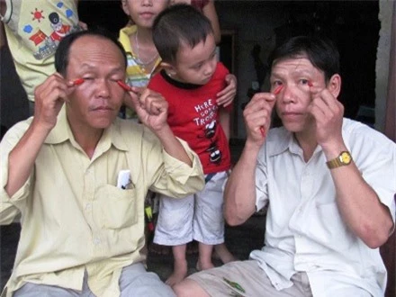 Anh Vinh (trái) và anh Khánh bắt đầu màn ăn ớt thay cơm và chà ớt lên mắt