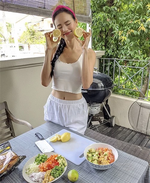 Người mẫu Tuyết Lan khoe vóc dáng mảnh mai khi tự tay thực hiện món gỏi cá. Áo crop-top thun được mix cùng quần linen tiệp màu, người mẫu chọn thêm băng đô hồng cánh sen để tôn nét nữ tính.