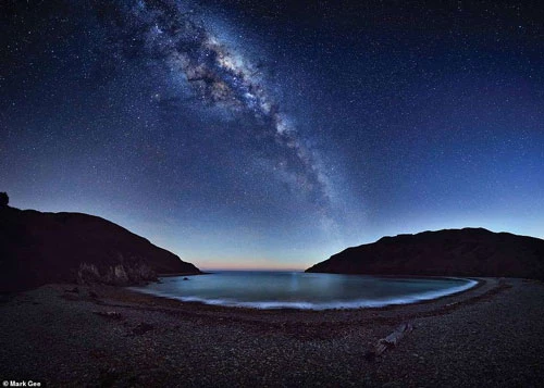 Dải ngân hà tráng lệ trải dài trên bầu trời đêm, phản chiếu xuống vịnh Cable, gần Nelson, New Zealand. Nhiếp ảnh gia đã chụp bức ảnh thiên văn trước khi vùng sáng tắt dần trên bầu trời.