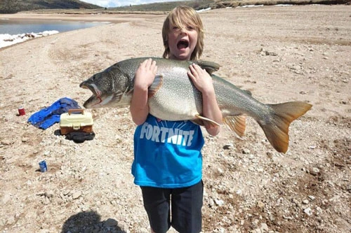 Bé Tanner chụp ảnh cùng con cá hồi mình vừa bắt được. Ảnh: CBS News.