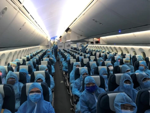 Tất cả hành khách, phi hành đoàn sử dụng đồ bảo hộ toàn thân và hạn chế giao tiếp, đi lại trong suốt chuyến bay. Ảnh: VNA.