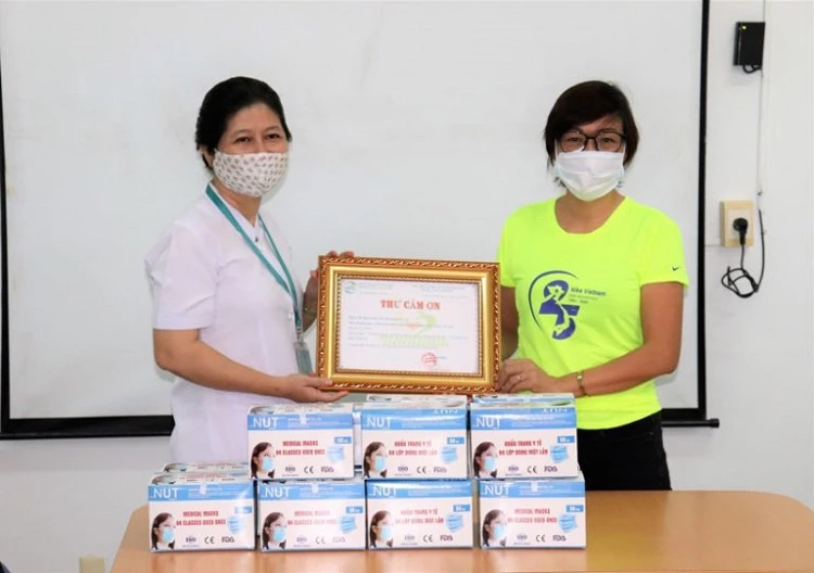Bà Vũ Thủy, Giám đốc đối ngoại Nike Việt Nam (bên phải) trao tặng khẩu trang y tế cho đội ngũ y bác sĩ tại Bệnh viện Nhiệt đới TP. Hồ Chí Minh.