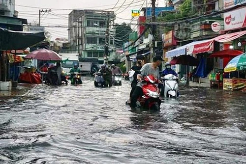 Mưa kéo dài khiến khu vực chợ Thủ Đức ngập nặng, nước chảy xiết làm người tham gia giao thông gặp rất nhiều khó khăn. Ảnh: Nhân dân.