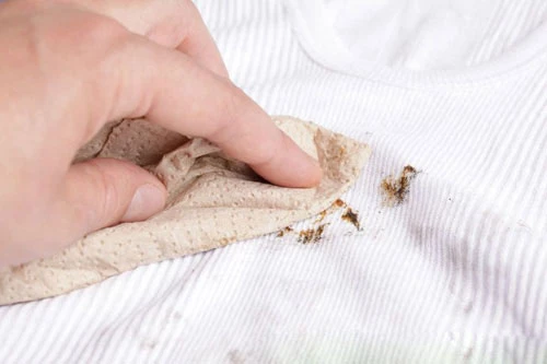 Bạn lấy khăn giấy lau qua vết dầu mỡ trên quần áo cần làm sạch.