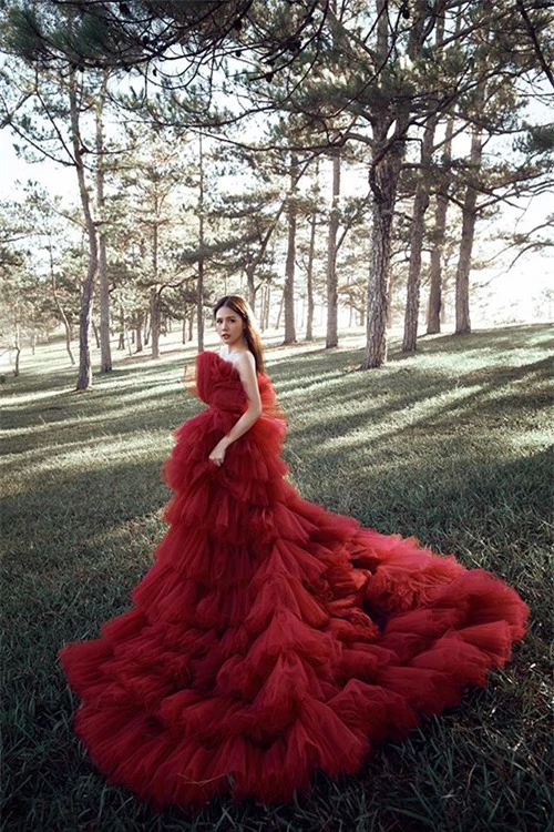 Bộ váy xếp tầng thướt tha màu đỏ khiến Phương Anh trở nên nổi bật trong khung cảnh huyền bí của rừng thông Đà Lạt lúc sớm mai.