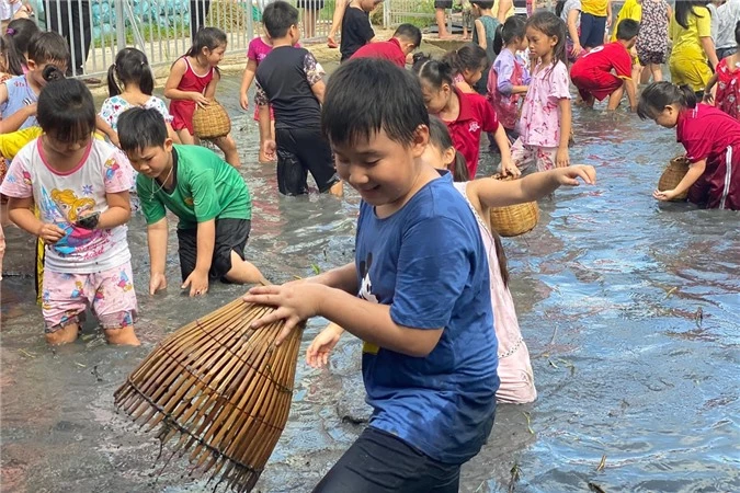 Cà Pháo không ngại lội xuống sình, dùng nơm bắt cá. Đìa cá này do nhà trường dựng lên, có giáo viên và phụ huynh giám sát nên đảm bảo an toàn cho các em học sinh.