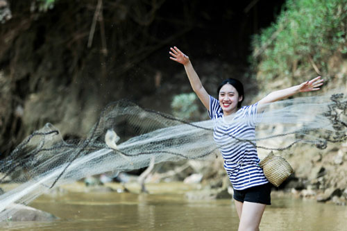 Khách du lịch thích thú trải nghiệm bắt cá suối dưới chân thác Dải Yếm