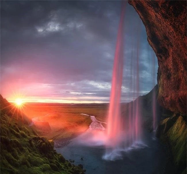 Hoàng hôn nửa đêm phản chiếu trong một thác nước ở Iceland
