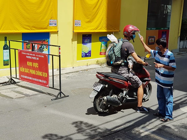 Đo thân nhiệt vầ rửa tay sát khuẩn đối với người vào khu vực kiểm soát phòng chống dịch trên đia bàn quận Sơn Trà, Đà Nẵng (Ảnh HC)