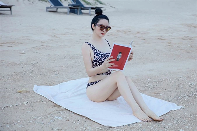 Mỹ nhân 7X vừa phơi nắng vừa đọc báo trên bãi biển vắng người.