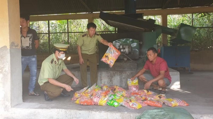 Công chức Đội QLTT số 6 phối hợp với đơn vị chức năng tiêu hủy số thực phẩm nhập lậu, ảnh: Bình Nguyên.