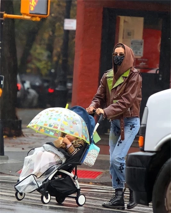 Cơn mưa nhỏ không làm cản trở Irina Shayk và bé Lea ra phố. Siêu mẫu đội mũ áo da kín đầu trong khi con gái tự che ô.