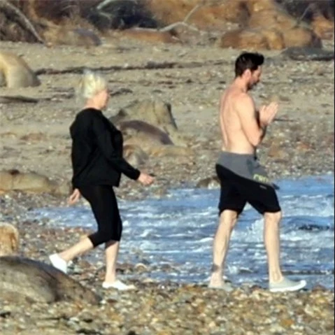 Hugh Jackman cởi trần trong khi vợ anh mặc cả bộ đồ đi xuống biển.