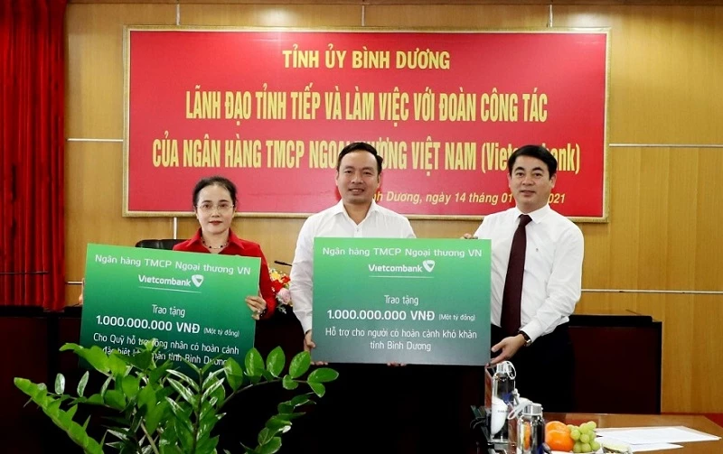 Chủ tịch Vietcombank Nghiêm Xuân Thành (bìa phải) trao bảng tượng trưng ủng hộ công nhân lao động và người có hoàn cảnh khó khăn trên địa bàn tỉnh Bình Dương. 