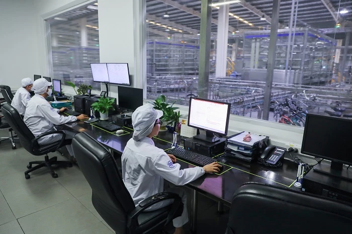 Các nhân viên tại nhà máy Vinamilk ở Bình Dương đang vận hành dây chuyền sản xuất sữa hiện đại hoàn toàn tự động hóa qua hệ thống máy tính.