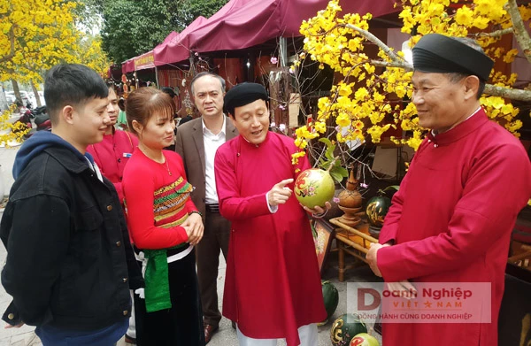 Anh Lê Việt Dũng trong trang phục áo dài ngũ thân truyền thống giới thiệu sản phẩm cho du khách.