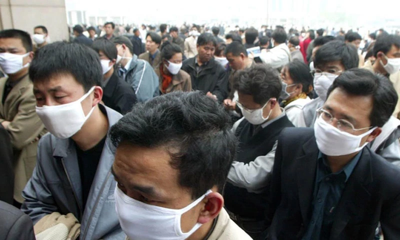 Ảnh: Người qua đường đeo khẩu trang để tự bảo vệ mình khỏi vi rút SARS trong khi chờ mua vé tại ga tàu Bắc Kinh, Thứ Tư, ngày 23 tháng 4 năm 2003. Greg Baker / AP