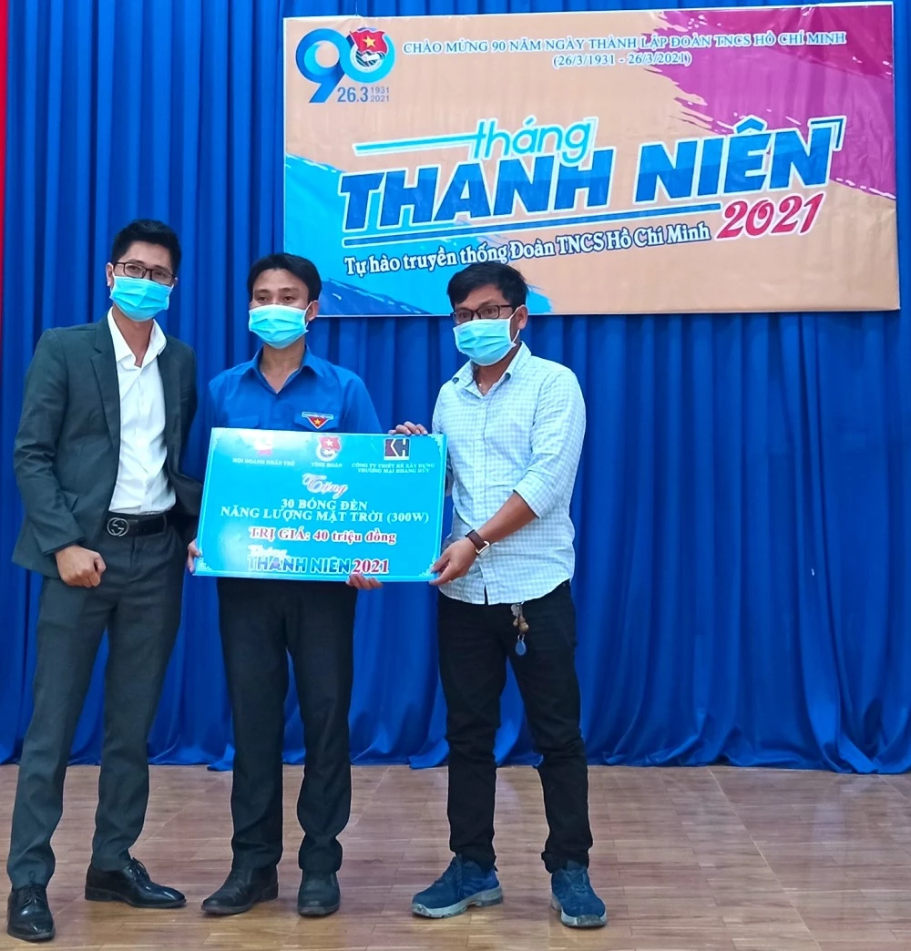 Ông Đào Trần Lanh - Chánh Văn phòng Hội Doanh nhân trẻ tỉnh Bình Phước (bìa trái) và ông Hà Văn Hải – Phó Giám đốc Công ty TNHH Thiết kế Xây dựng và Thương mại Khang Huy (bìa phải) trao bảng tượng trưng 30 bóng đèn năng lượng mặt trời cho anh Lê Thanh Hoàng - Bí thư huyện Đoàn Hớn Quản.